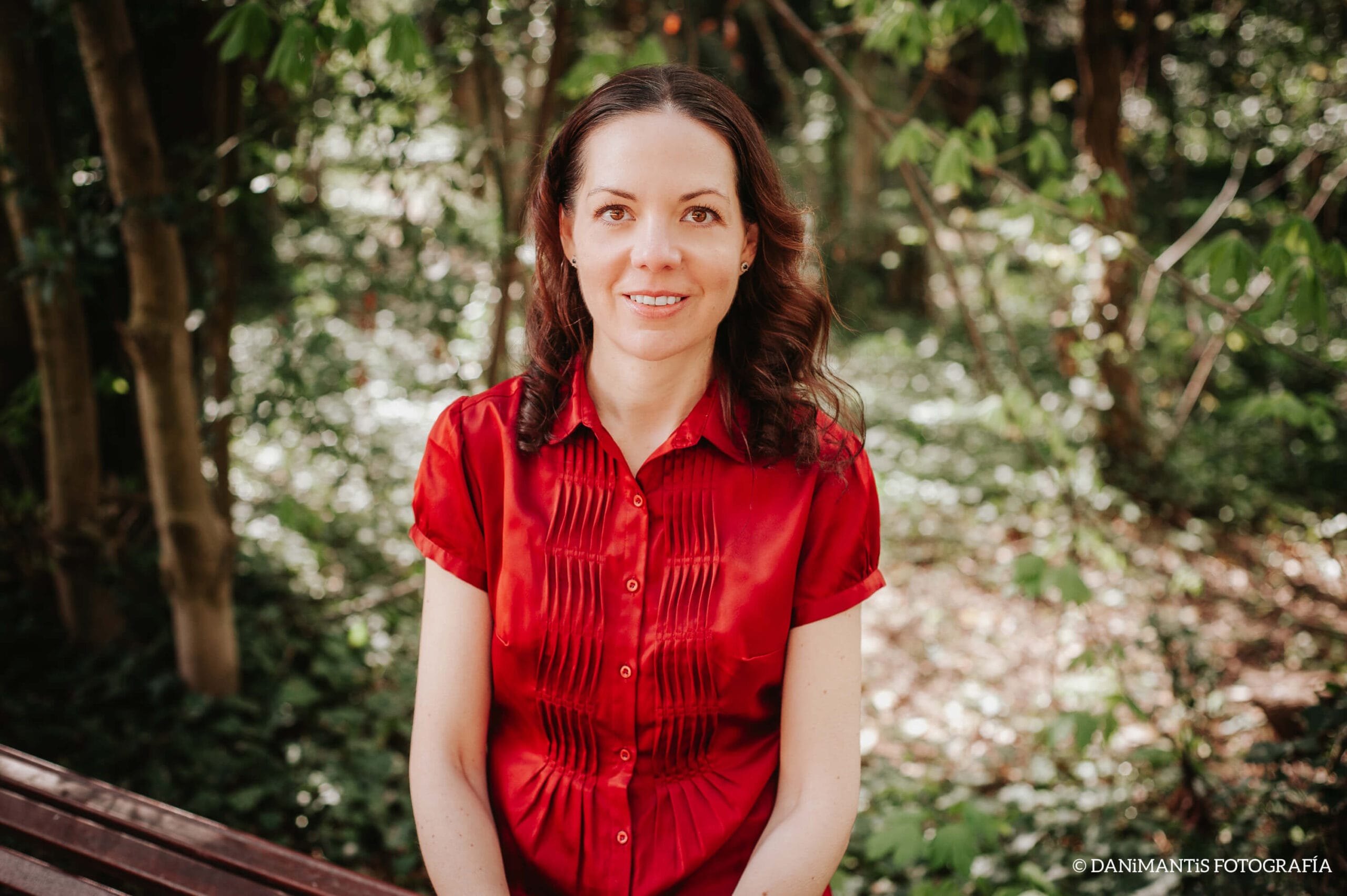 Ritratto di Laura, coautrice di Carolina Purpurina, con una camicia rossa in giardino.