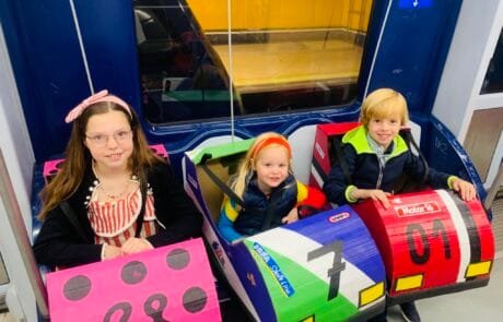 Carolina e i suoi fratelli viaggiano in metropolitana con i loro costumi da autoscontro diretti al concorso.