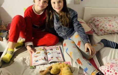 Isabel e la sua amica Martina, illustratrice del libro, sfogliano insieme un catalogo sedute sul letto.