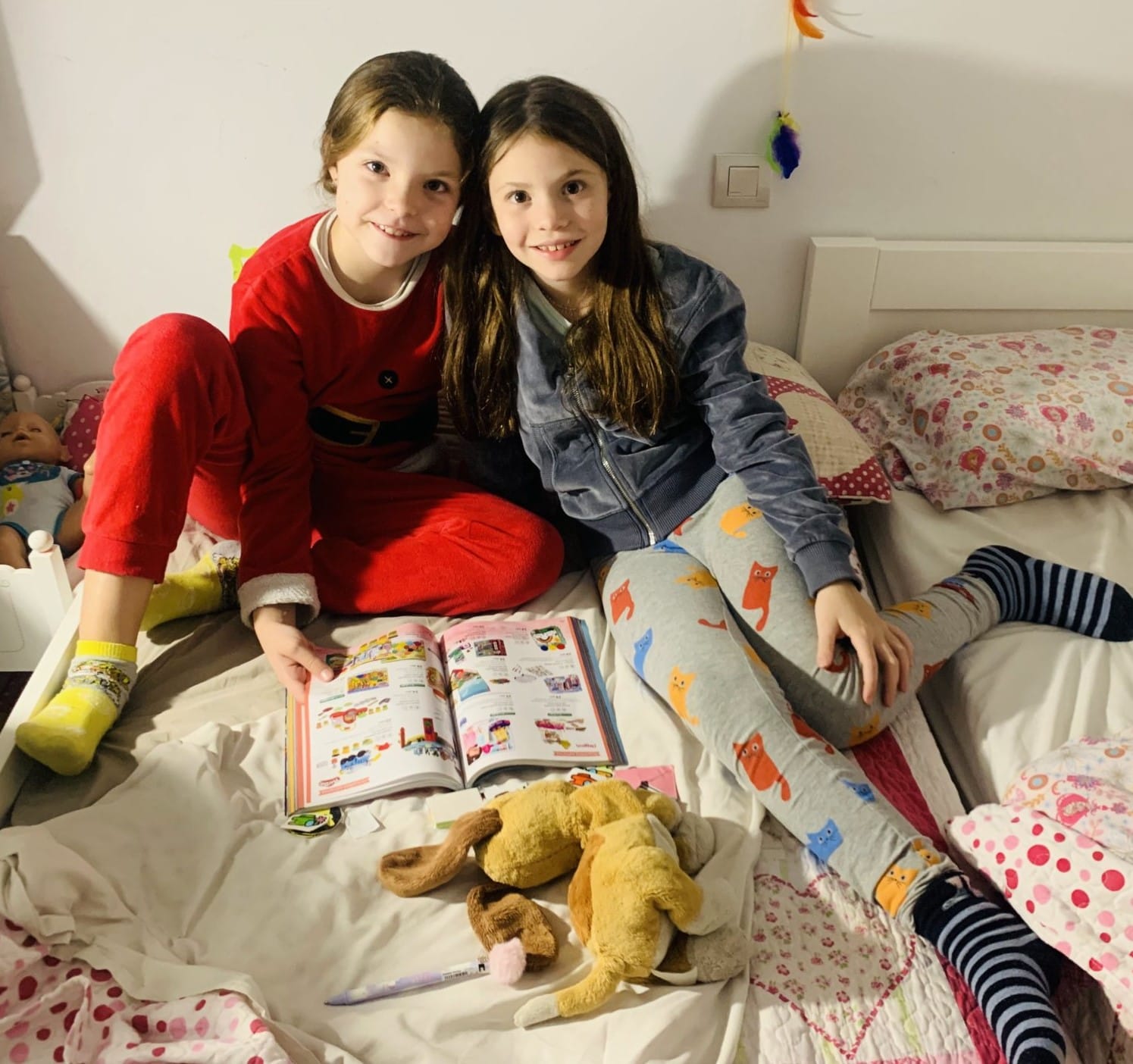 Isabel e la sua amica Martina, illustratrice del libro, sfogliano insieme un catalogo sedute sul letto.
