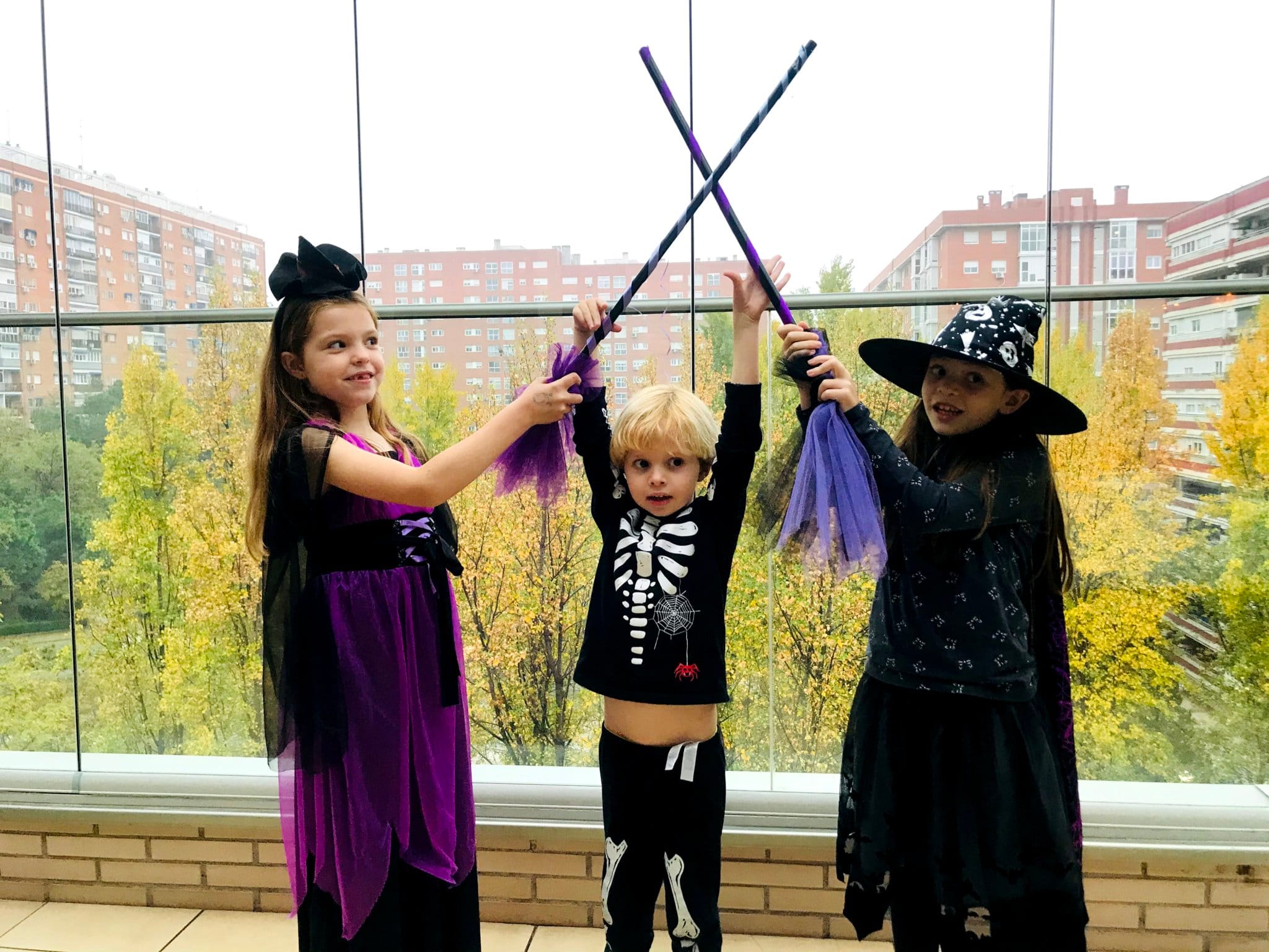 Giochi con le scope al compleanno di Carolina Purpurina: tre bambini travestiti incrociano le loro scope da strega.
