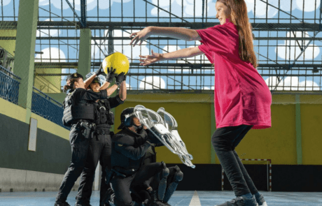 Fotografia del calendario ELA 2024: Carolina lancia un pallone ad agenti della Guardia Civil in un palazzetto.