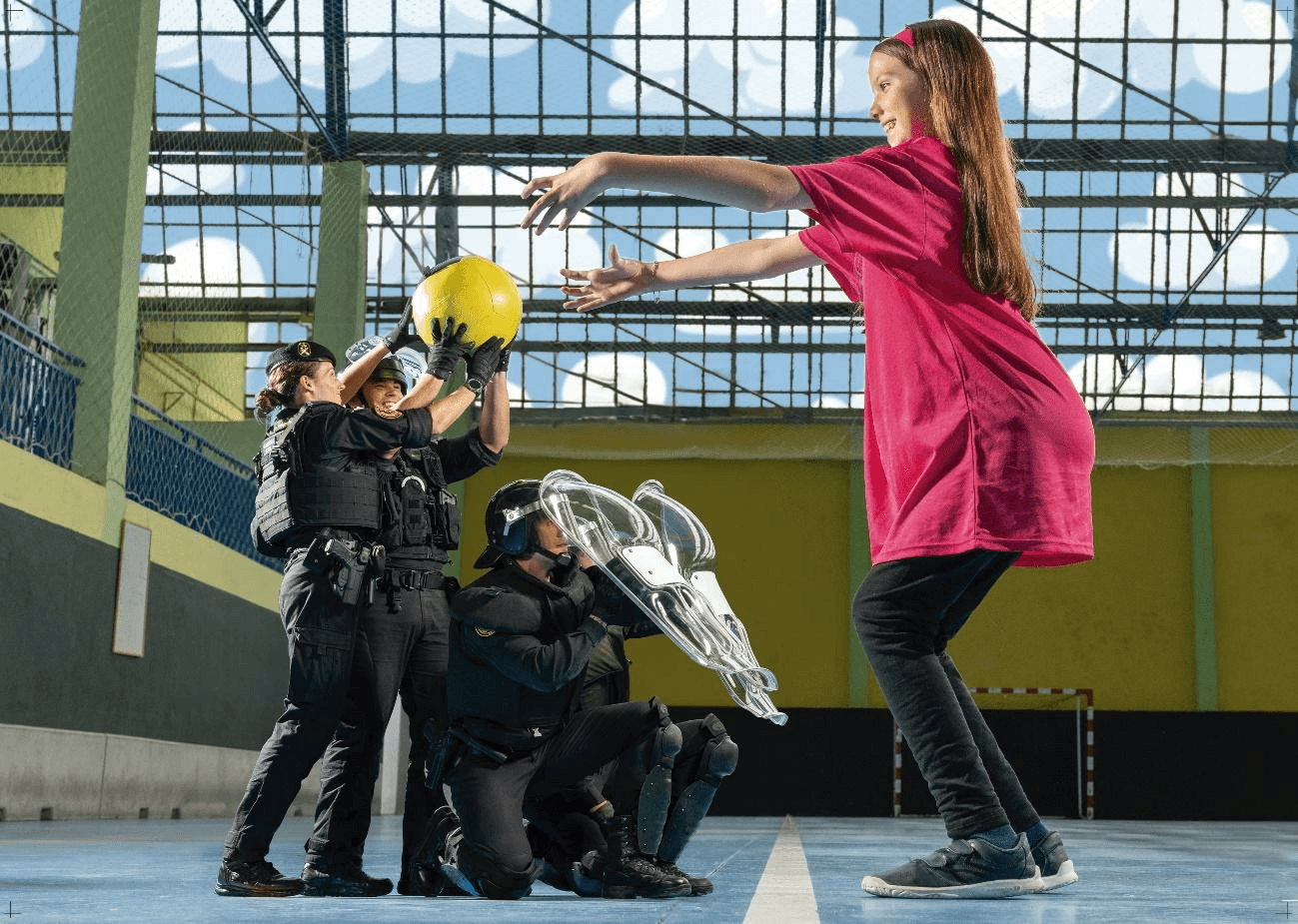 Fotografia del calendario ELA 2024: Carolina lancia un pallone ad agenti della Guardia Civil in un palazzetto.