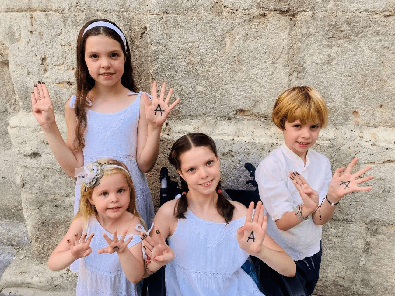 Carolina e i suoi fratelli posano con le lettere della Fundación Tubb4a dipinte sulle mani per il calendario 2024.