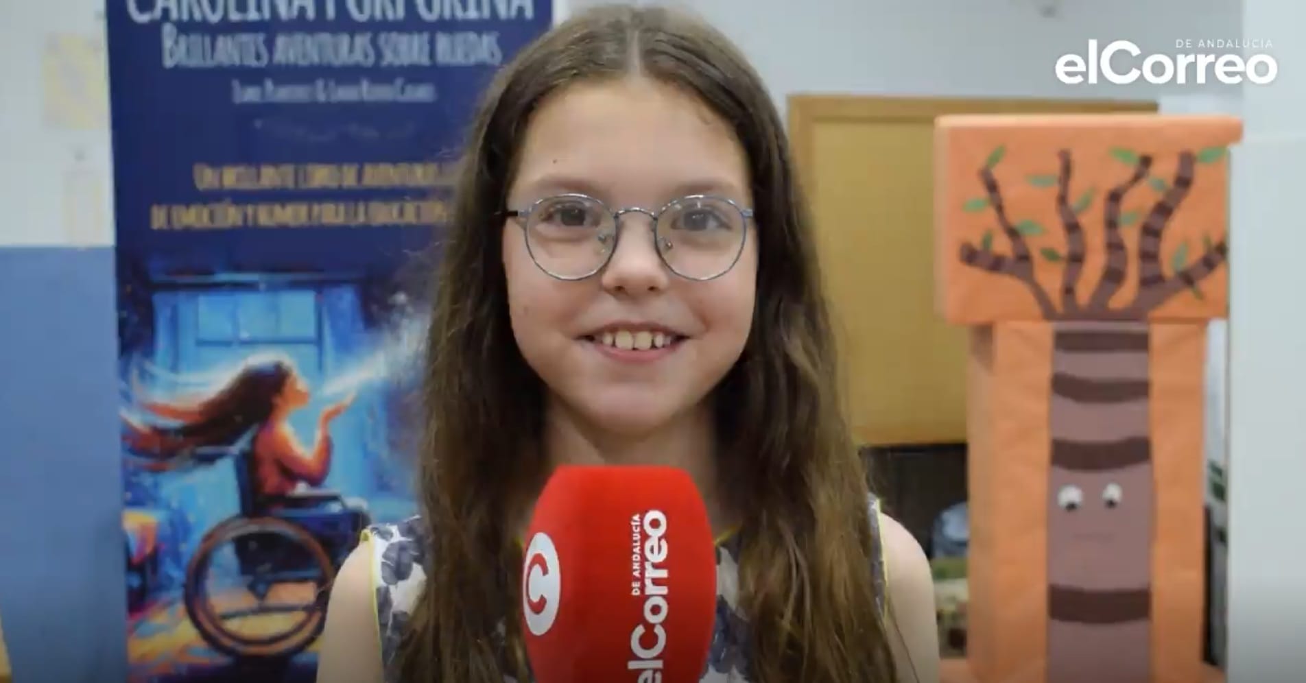 Isabel, con i suoi occhiali rotondi, risponde davanti al microfono di elCorreo de Andalucía, accanto al roll-up del libro.