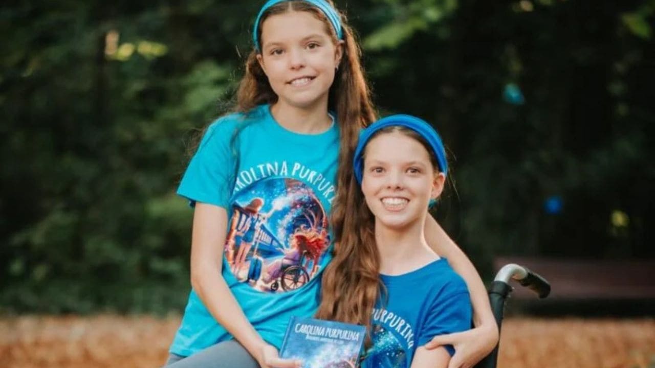 Isabel e Carolina, con le magliette di Carolina Purpurina, tengono il libro in un parco.