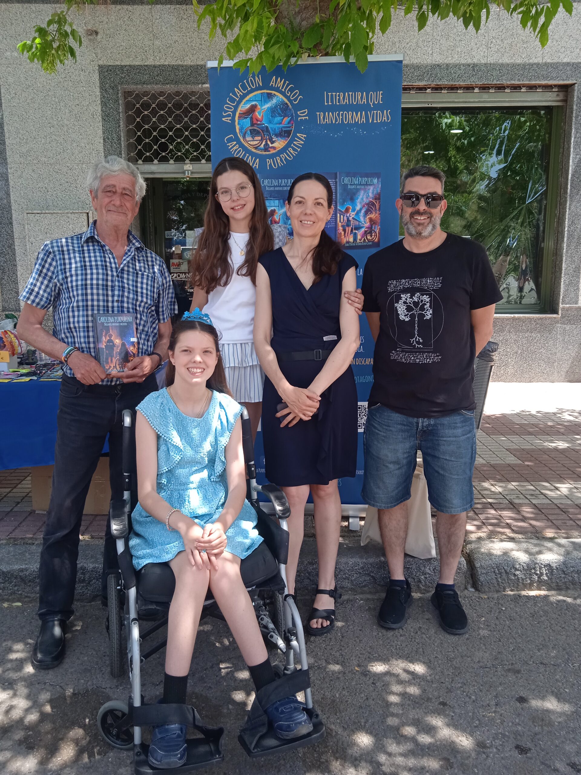 Presentazione del libro: la famiglia posa davanti al roll-up dell'Asociación Amigos de Carolina Purpurina.
