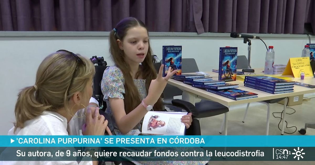 Servizio di Canal Sur a Cordova: una bambina seduta, con il libro aperto, parla con una donna; dietro, il tavolo con le copie del libro.