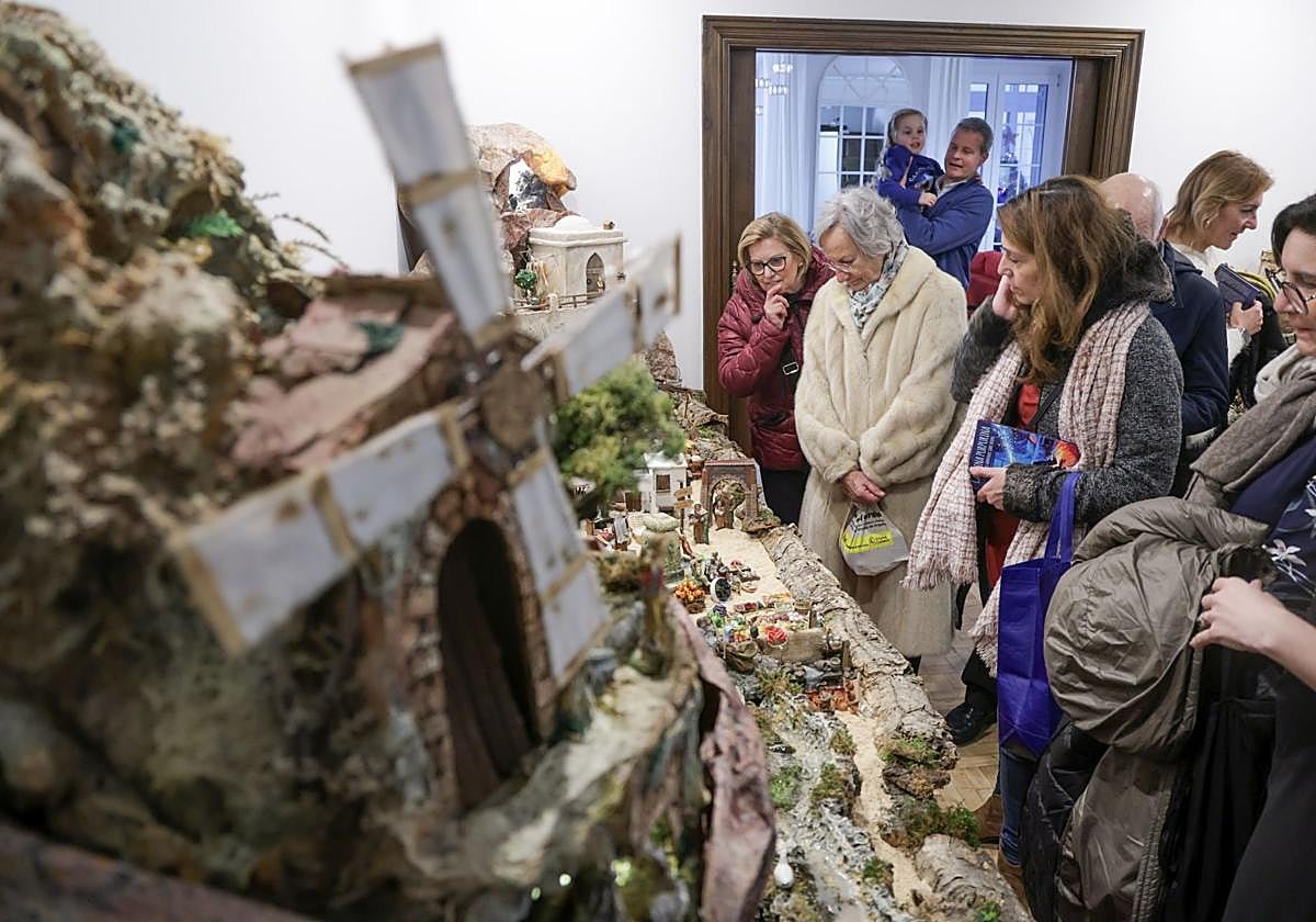 Visitatori osservano il grande presepe della famiglia, con un mulino in primo piano, durante la giornata a porte aperte.