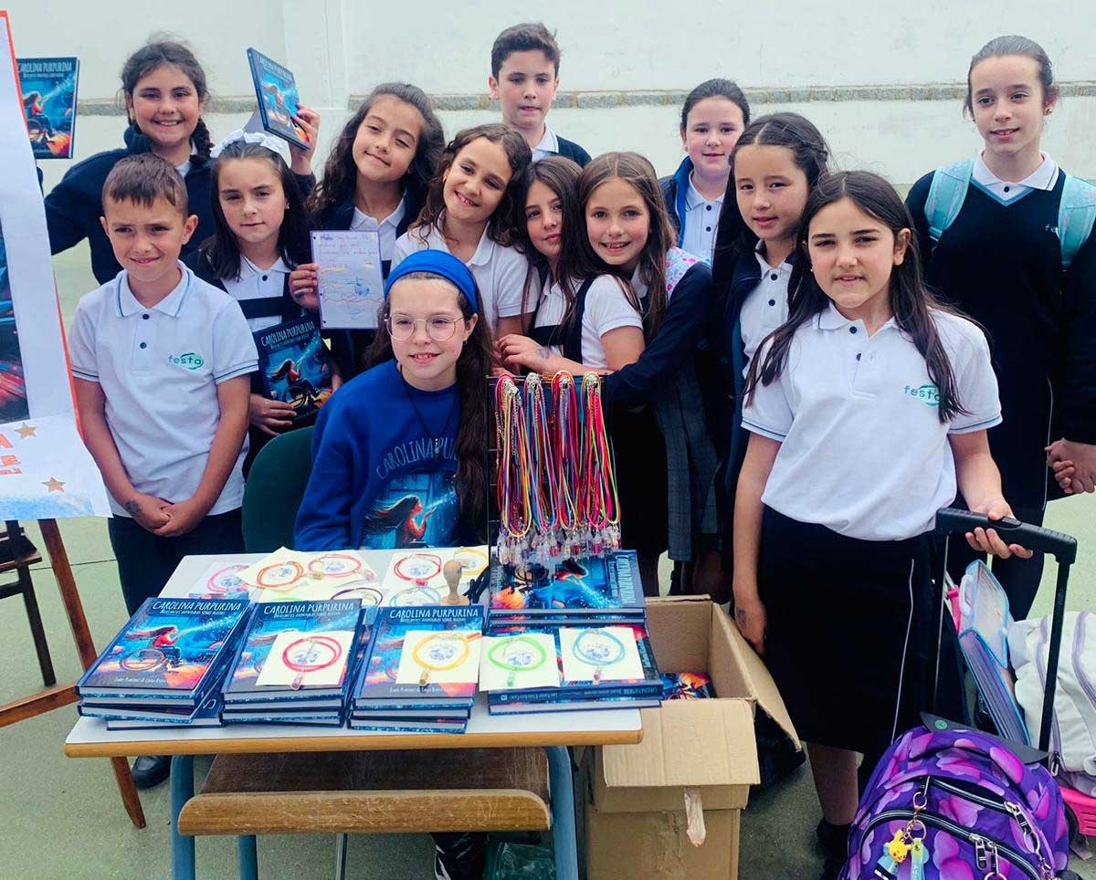 Visita alla scuola Presentación de María: una bambina, dietro il tavolo di libri e braccialetti, circondata da alunni in divisa.